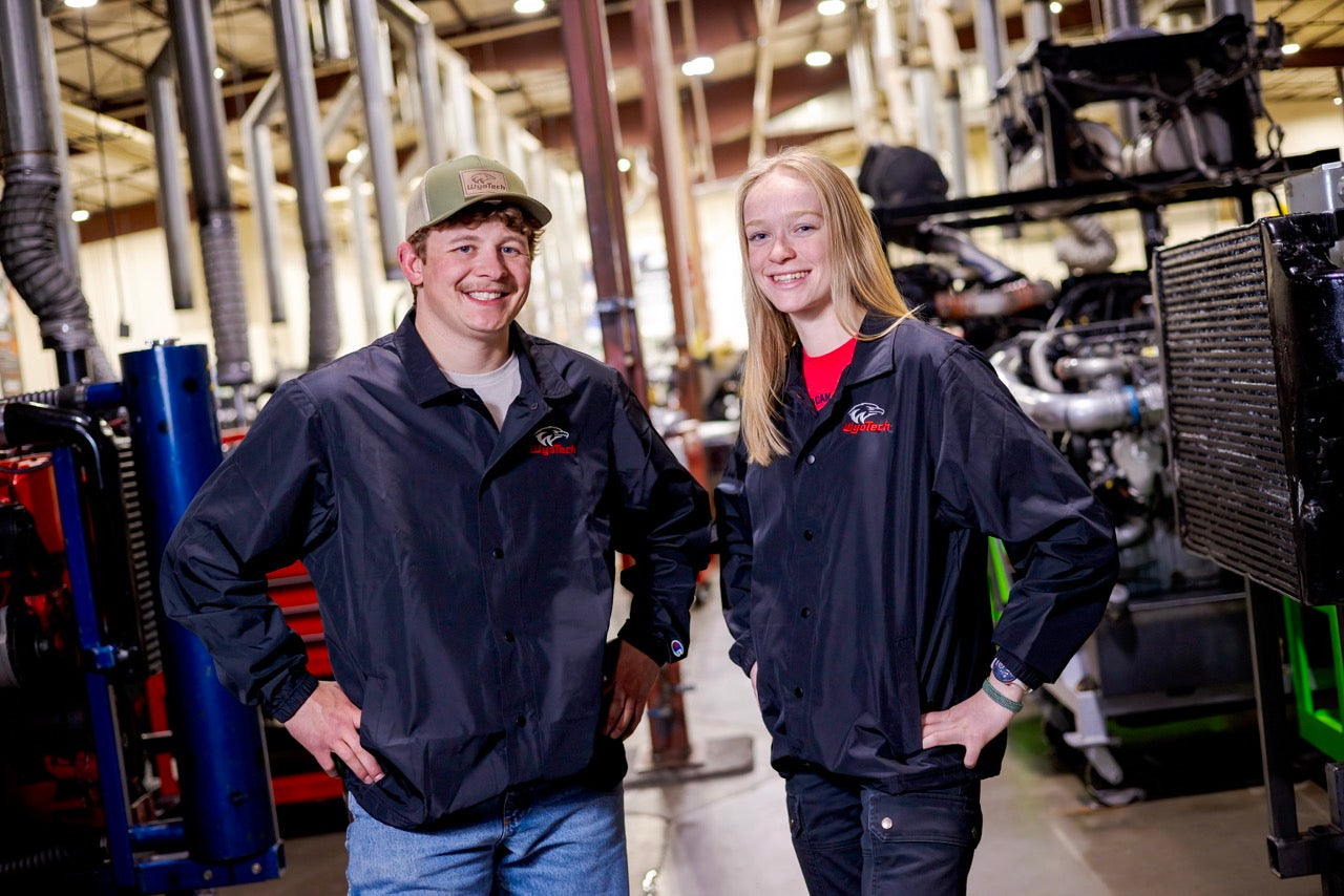 Two WyoTech studentswearing WyoTech jackiets in an auto shop.